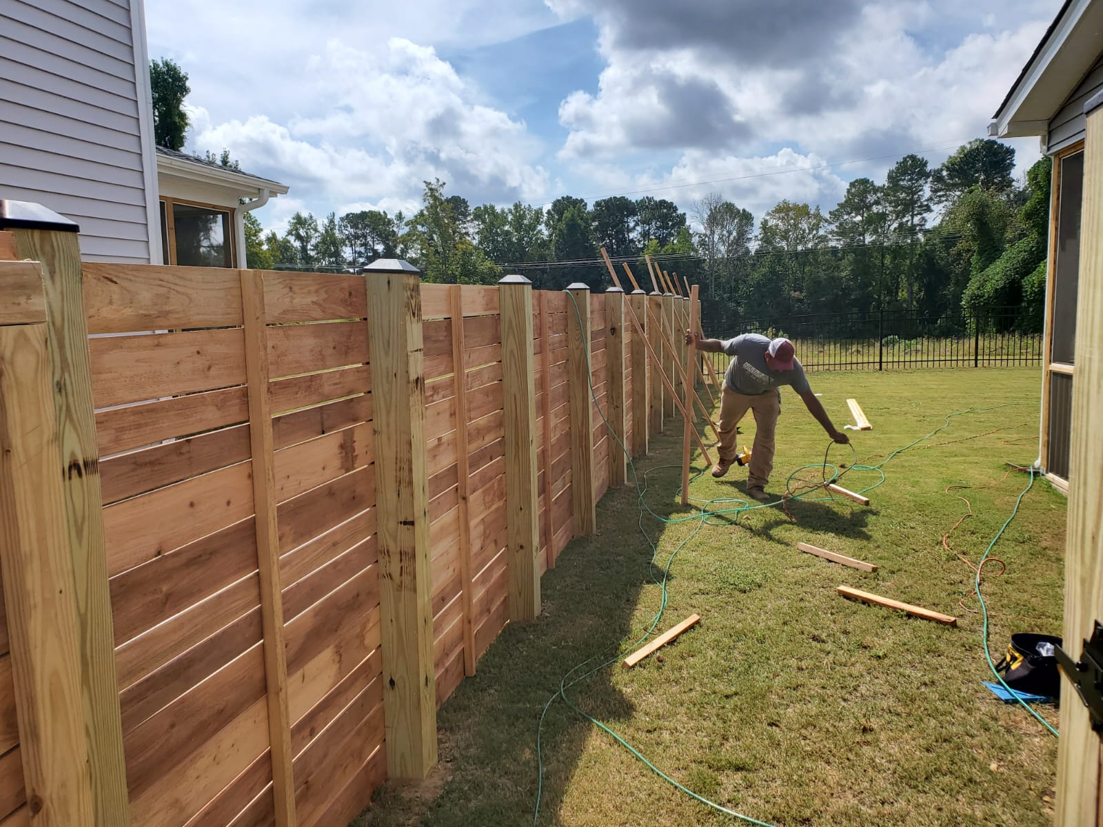 Fitting a new fence panel between two sound posts during a fence panel replacement
